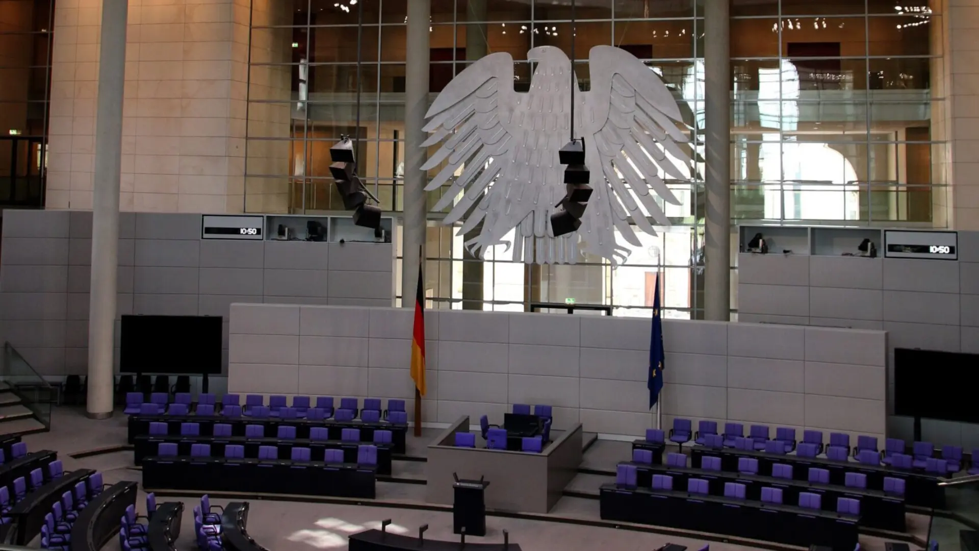 Innenansicht des leeren Plenarsaals des Deutschen Bundestages mit dem Bundesadler im Hintergrund