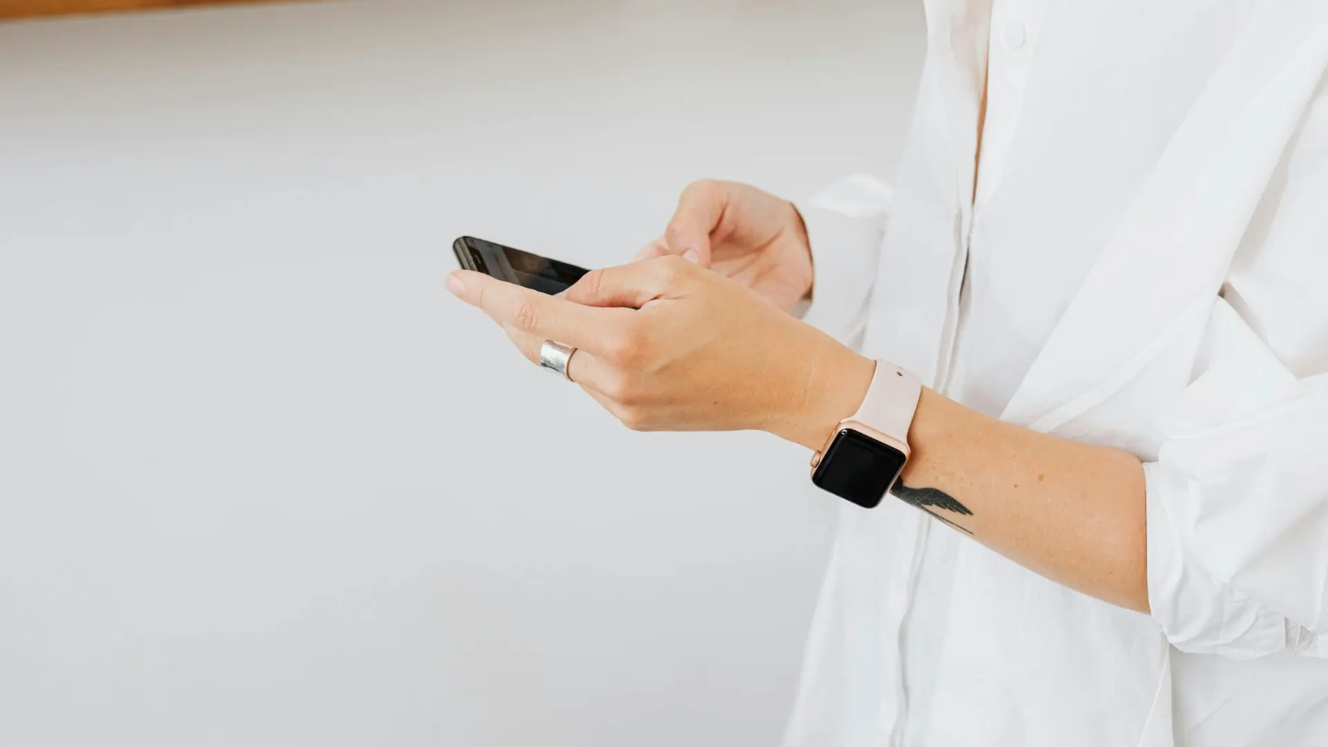 Nahaufnahme einer Person im weißen Hemd, die ein Smartphone bedient – Symbol für mobile Abrechnung und Digitalisierung