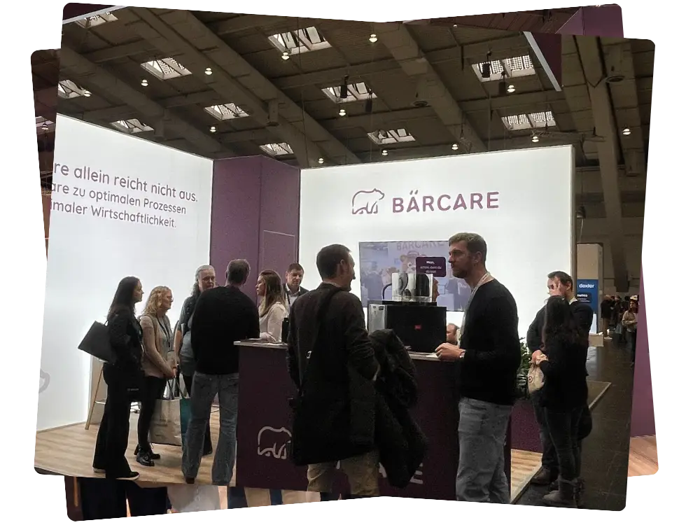 Besucher und Teammitglieder am hell beleuchteten Bärcare Messestand auf einer Fachmesse für die Pflegebranche.